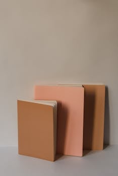 Aesthetic minimalistic photo of three pastel-colored notebooks against a neutral background.