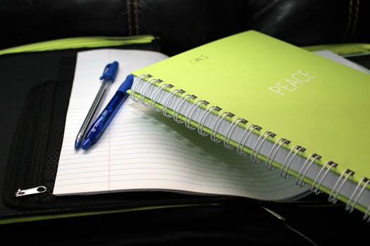 Green spiral notebook labeled 'PEACE' with pens on lined paper.